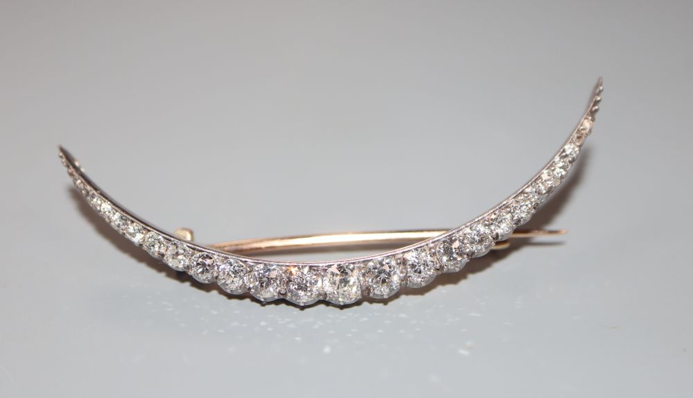 An Edwardian yellow metal and graduated diamond set crescent brooch, 57mm, gross 4.4 grams.